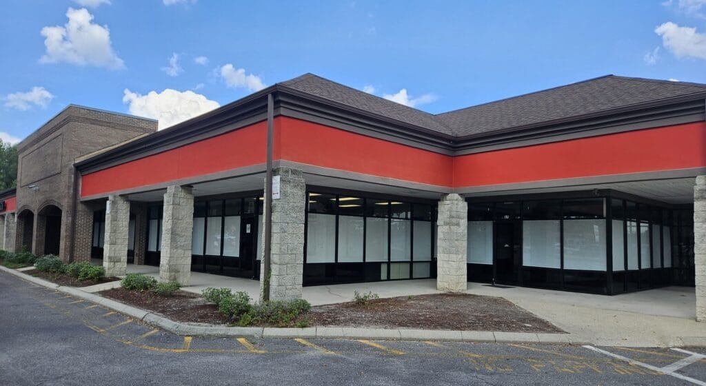 Vacant retail building with a red facade and large windows, located in a shopping area. Relevant for discussions about commercial real estate.